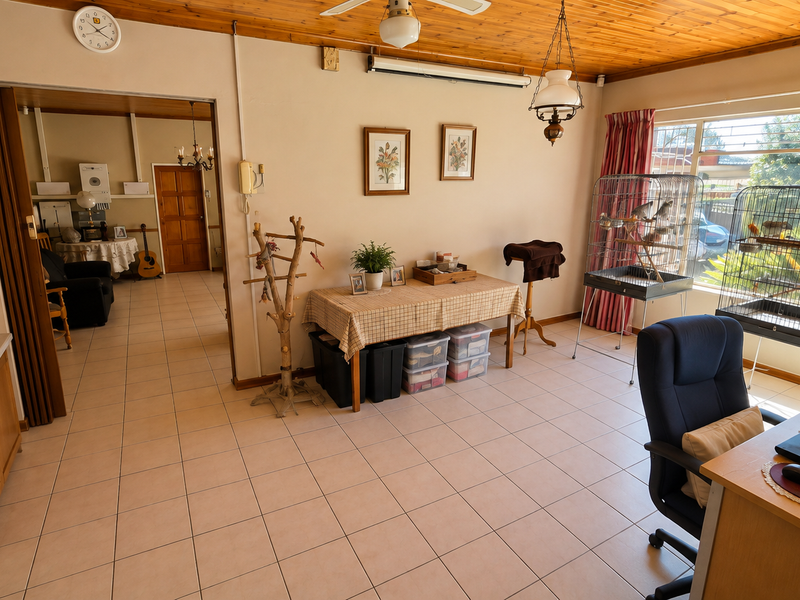 A living area featuring ceramic floor tiles, a timber-clad ceiling, and a folding door leading to an adjacent room with security-barred windows.