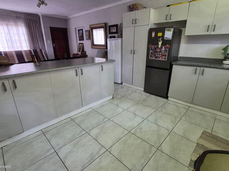A functional kitchen featuring light-toned built-in cabinetry, laminate countertops, and tiled flooring, offering a practical layout with ample storage space.