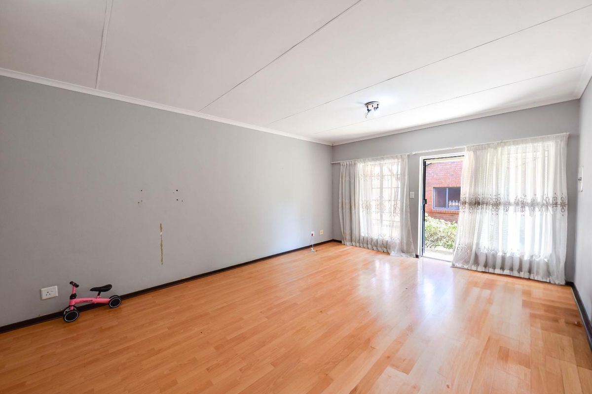 Spacious living room featuring laminate flooring and a sliding glass door providing access to the exterior, offering a blank canvas for interior design.