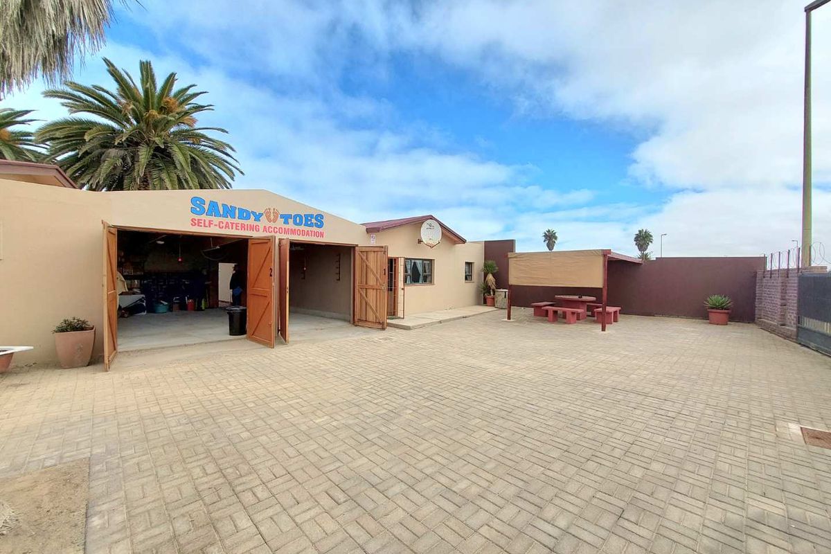Spacious paved courtyard area featuring a large garage entrance, outdoor seating space, and perimeter walling, suitable for guest parking or recreation.