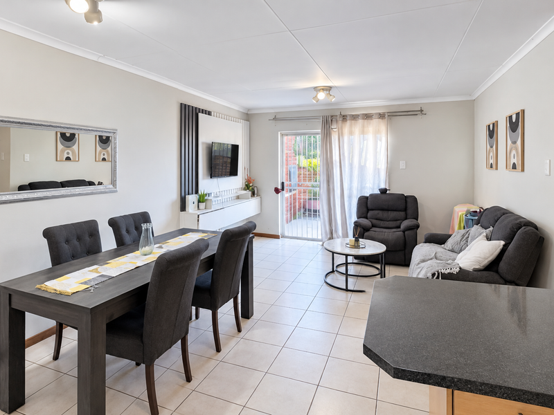 Spacious open-plan living and dining area featuring tiled flooring, a built-in media console, and direct access to an outdoor patio through a sliding glass door.