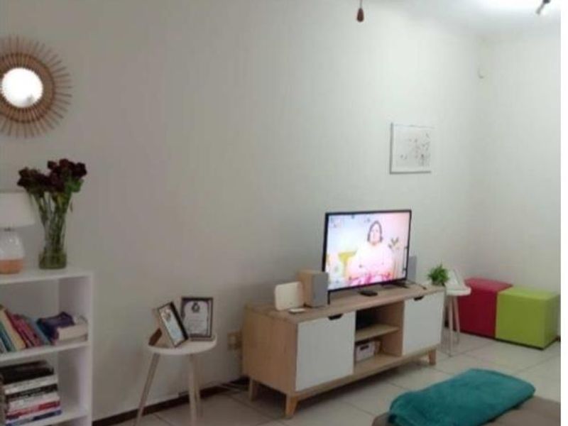 A living room area featuring neutral tiled flooring and plain white walls, providing a functional and bright space for relaxation.