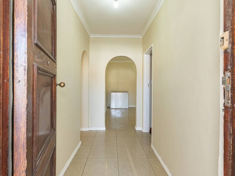 A functional hallway featuring tiled flooring and an arched transition leading to an adjacent space, finished with neutral wall tones.
