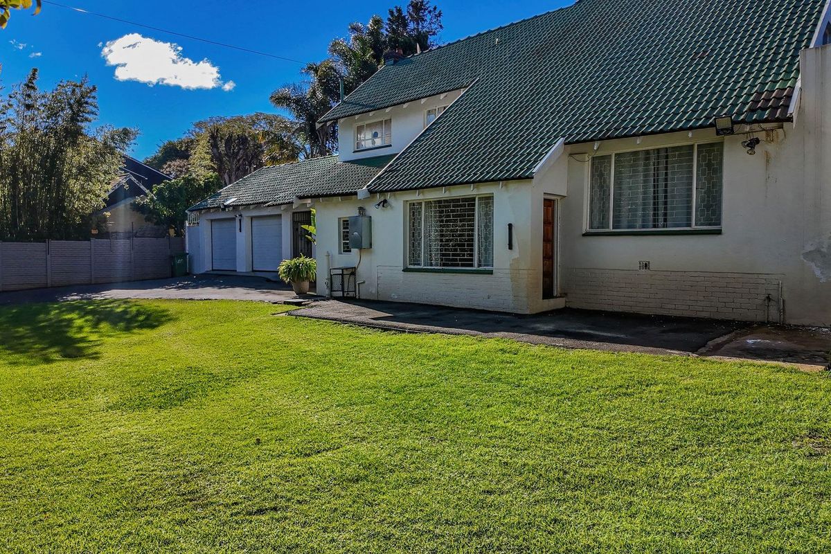 A view of the rear exterior of the house featuring a green tiled roof, white facade, and an attached double garage.
