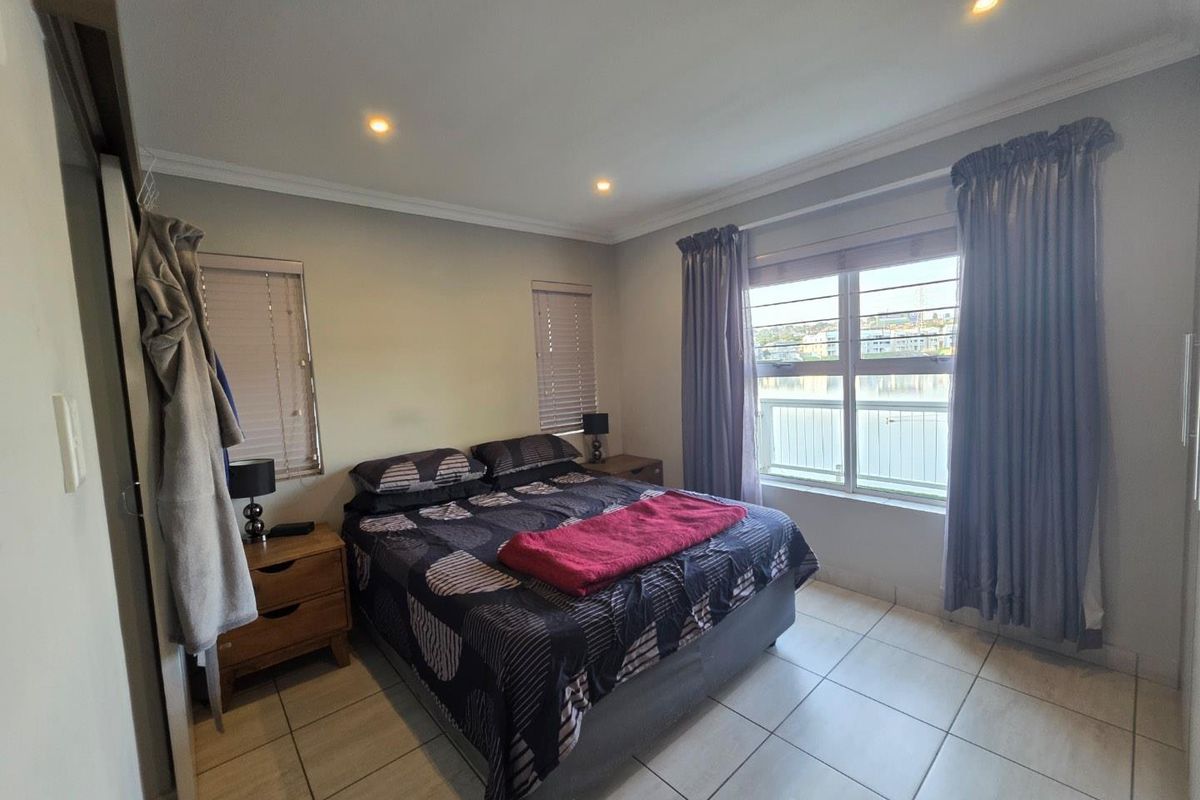A well-lit bedroom featuring tiled flooring, built-in cupboards, and large windows that provide natural light and views.
