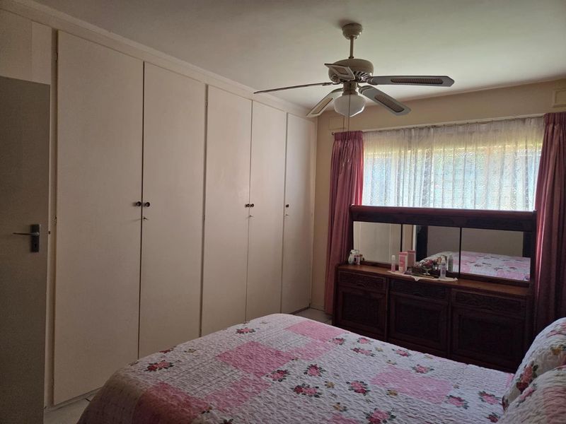 A bedroom featuring extensive built-in cupboards and a ceiling fan, offering functional storage space with a traditional layout.