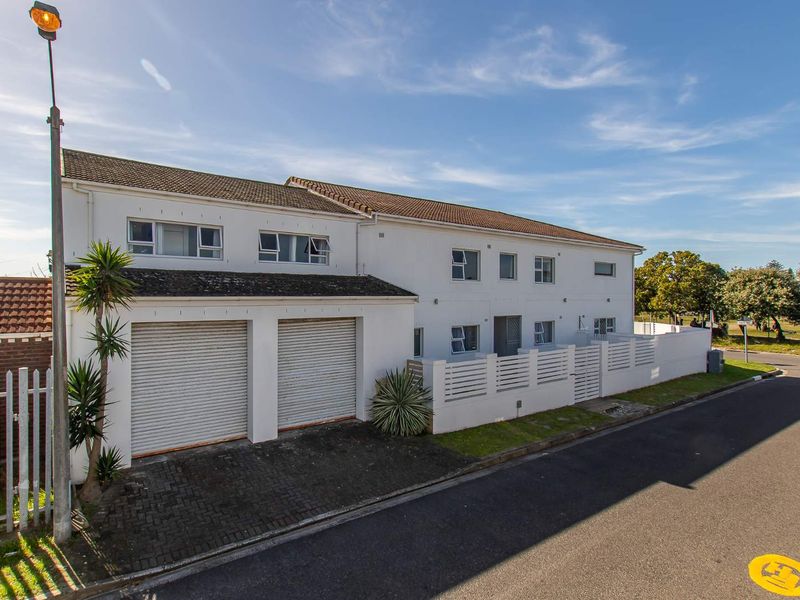 Front exterior view of a two-story residential property featuring a double garage with roller shutter doors and a perimeter wall.