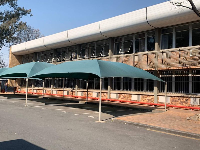 Industrial building exterior featuring brick facade, security-barred windows, and dedicated shade cloth parking bays.
