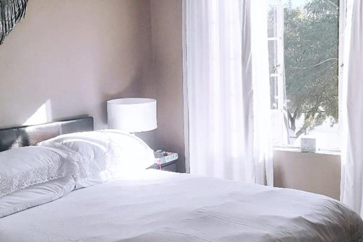 A well-lit bedroom featuring tiled flooring, neutral wall tones, and a large window that allows for natural light.