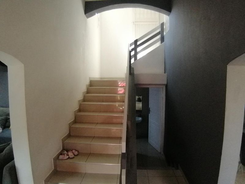 A tiled staircase with a wooden balustrade and arched architectural detail leading to an upper level.
