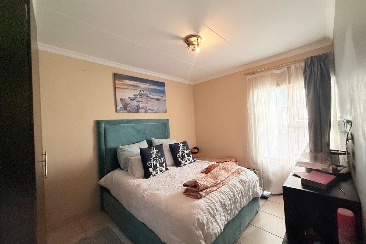 A standard bedroom featuring tiled flooring, a built-in cupboard, and a window with curtain tracks, providing a functional living space.