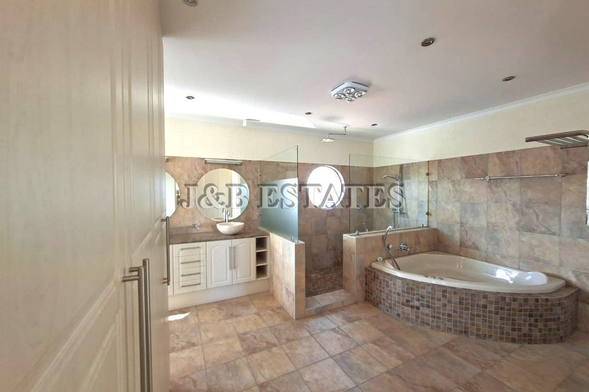 Spacious bathroom featuring a corner bathtub, walk-in glass shower, dual vanity with vessel sinks, and tiled flooring throughout.