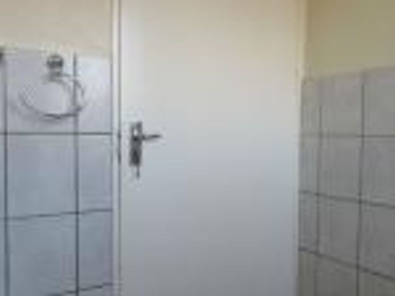 A functional bathroom space featuring tiled walls, a towel ring, and a towel rail, currently in need of cosmetic updates.