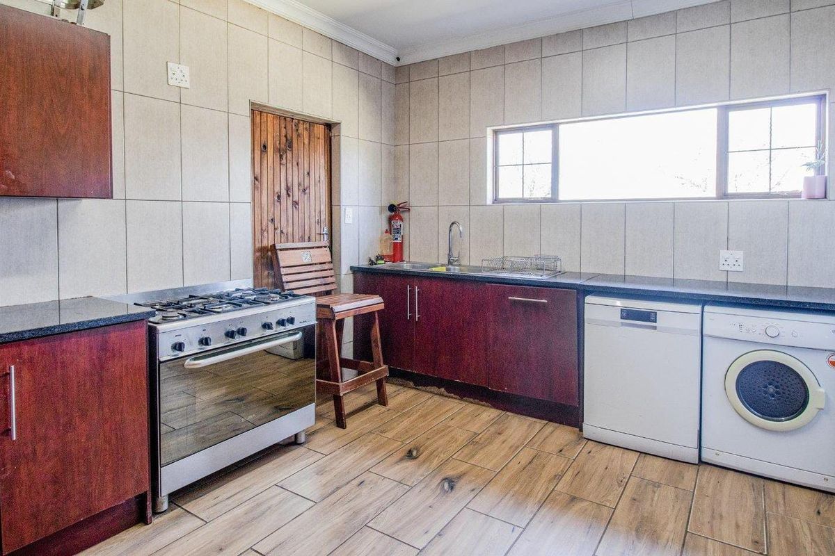 A functional kitchen featuring dark wood cabinetry, granite countertops, gas stove, and tiled finishes, providing a practical workspace for daily meal preparation.