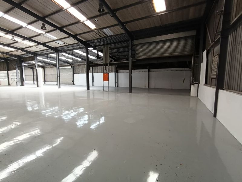 Spacious industrial warehouse featuring a polished epoxy floor, high-clearance steel portal frame, roller shutter access, and ample natural light through integrated skylights.