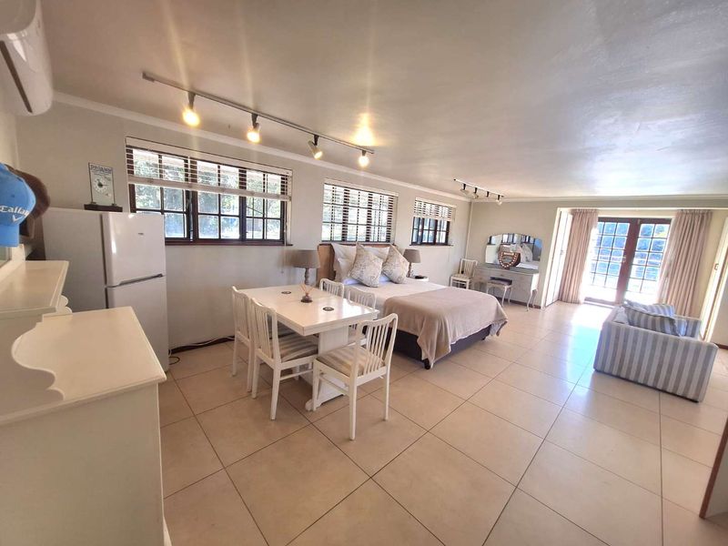 Spacious open-plan studio apartment featuring tiled flooring, track lighting, and direct access to an outdoor area through classic french doors.