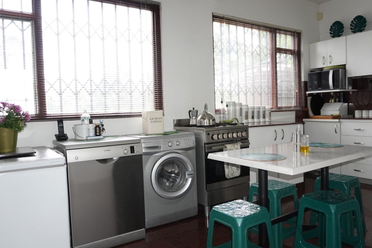 A functional kitchen featuring white cabinetry, a stainless steel gas stove, and security bars on the windows, providing a practical workspace.
