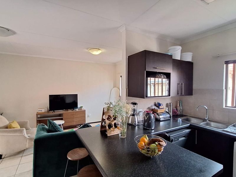 Open-plan living area featuring a functional kitchen with dark cabinetry, laminate countertops, and integrated appliances, seamlessly flowing into the adjacent living space.