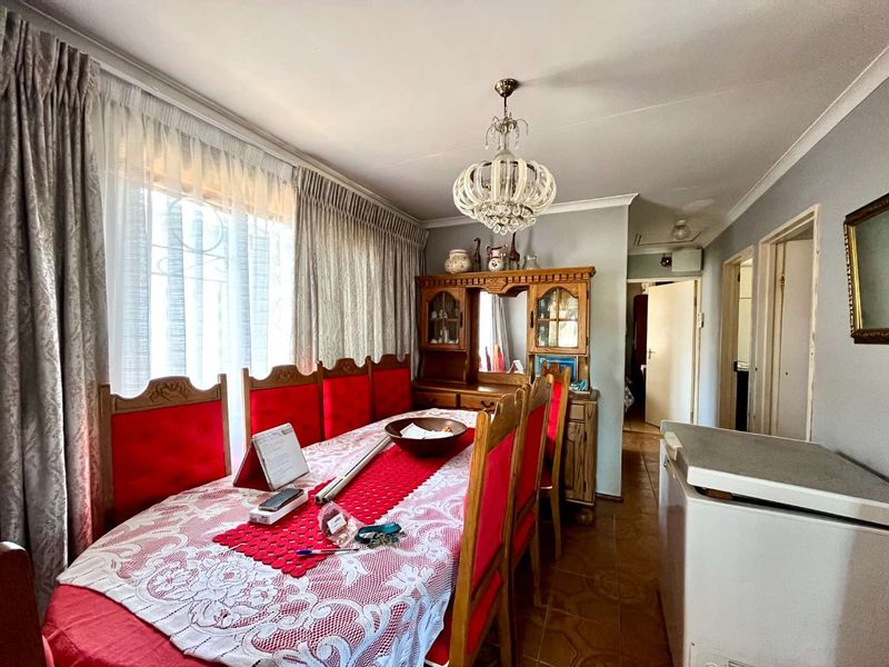 A traditional dining room featuring tiled flooring, coved cornicing, and a decorative crystal chandelier, providing a functional space for family meals.