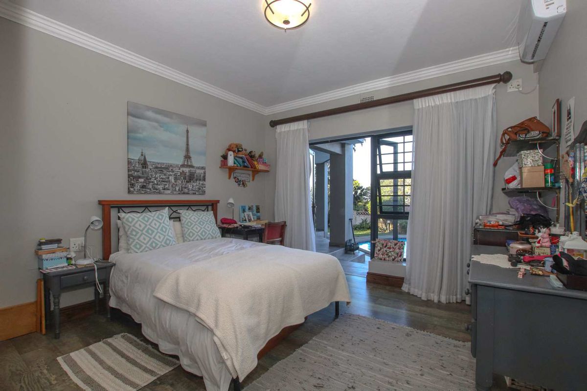 A bedroom featuring crown molding, tiled flooring, and a sliding door providing direct access to an outdoor patio and pool area.