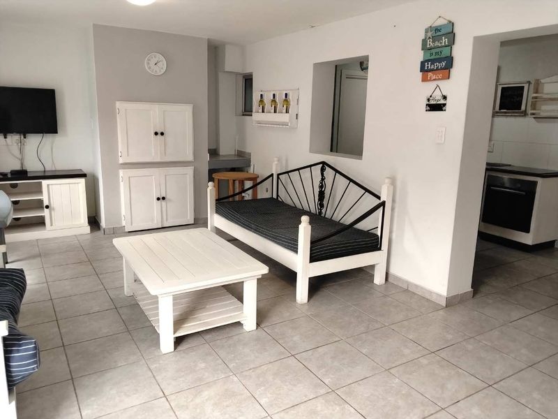Open plan living area featuring tiled flooring and built-in cabinetry, with a partial view into the adjacent kitchen space.