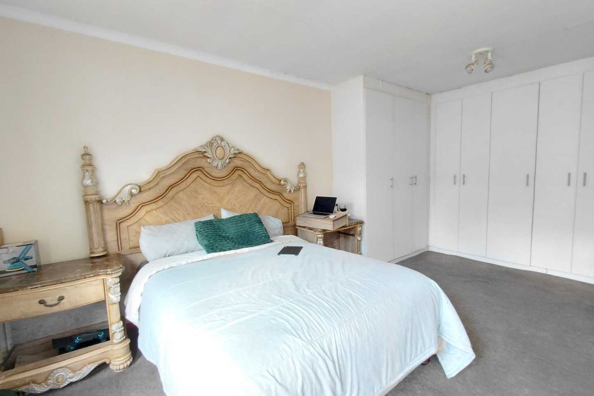 Spacious bedroom featuring built-in floor-to-ceiling wardrobes and neutral carpeting, offering a functional layout with ample storage space.