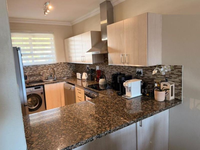 Functional kitchen featuring granite countertops, mosaic tile backsplash, stainless steel extractor fan, and integrated cabinetry with built-in oven and hob.
