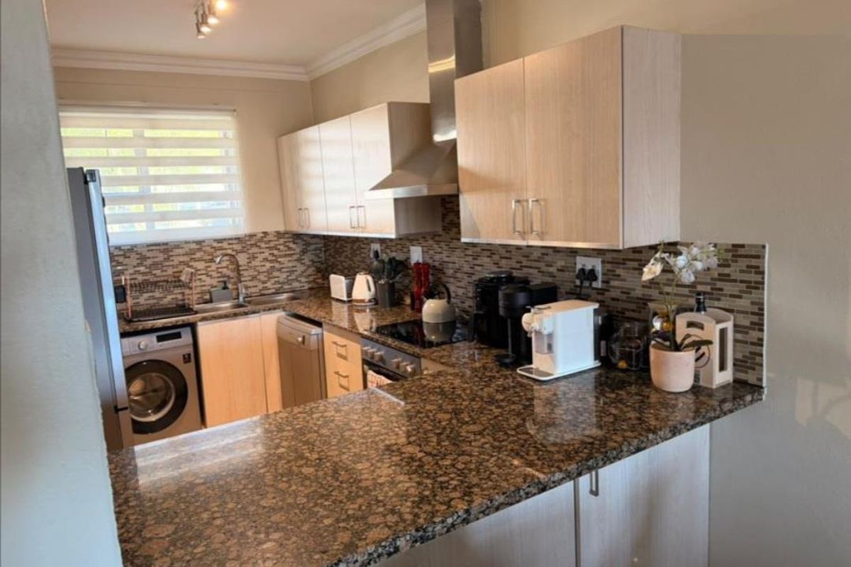 Functional kitchen featuring granite countertops, mosaic tile backsplash, stainless steel extractor fan, and integrated cabinetry with built-in oven and hob.