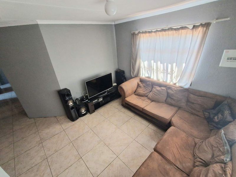 A functional living room featuring neutral tiled flooring and grey painted walls, providing a blank canvas for potential interior updates.