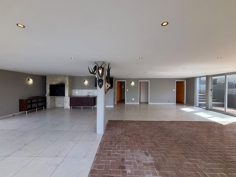 Spacious open-plan living area featuring a built-in fireplace, kitchenette, tiled and brick flooring, and large sliding glass doors leading to the exterior.
