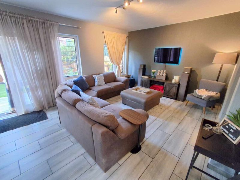 A comfortable living room featuring modern tiled flooring, an accent wall, and large sliding glass doors that provide access to the outdoor area.