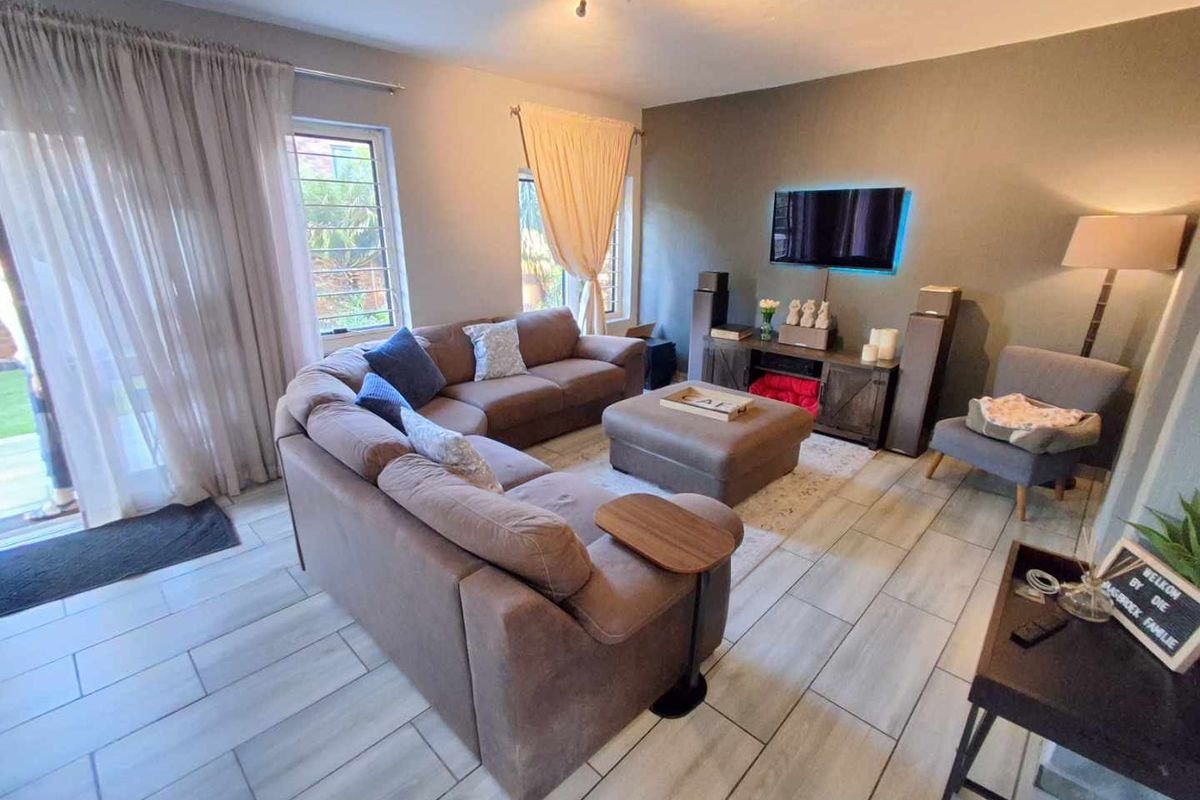 A comfortable living room featuring modern tiled flooring, an accent wall, and large sliding glass doors that provide access to the outdoor area.