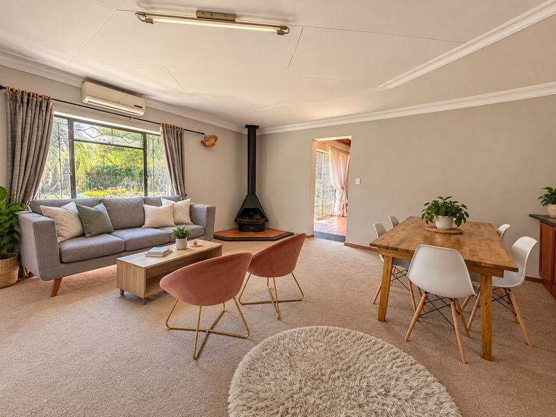 Spacious open-plan living and dining area featuring a cozy freestanding fireplace, neutral carpeting, and a split-system air conditioner for year-round comfort.