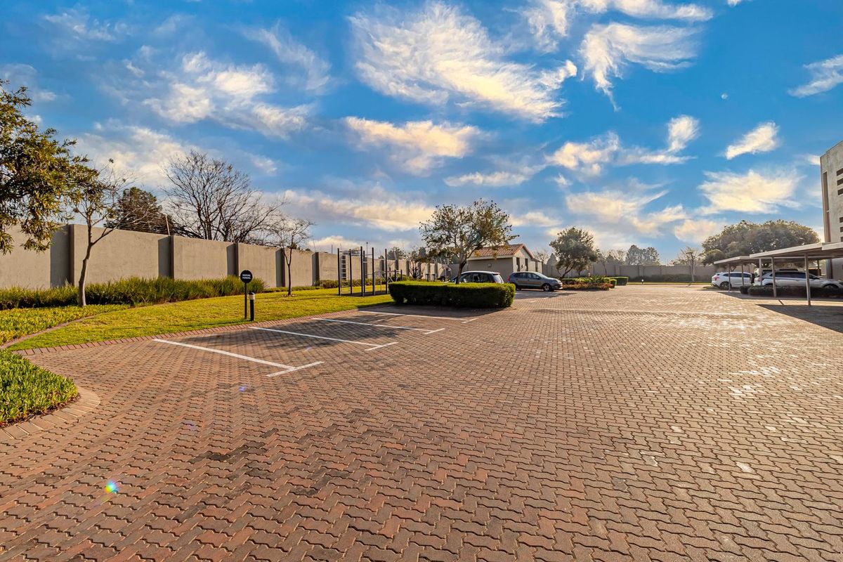 A well-maintained paved parking area within the apartment complex grounds, featuring marked bays and landscaped perimeter fencing.
