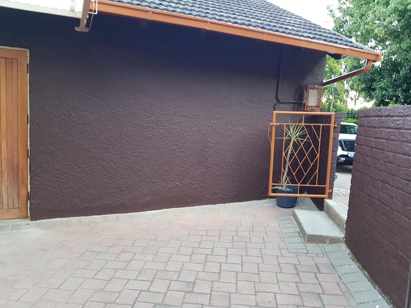 Exterior view of the property featuring a paved driveway, dark textured facade, and a secure gated entrance.