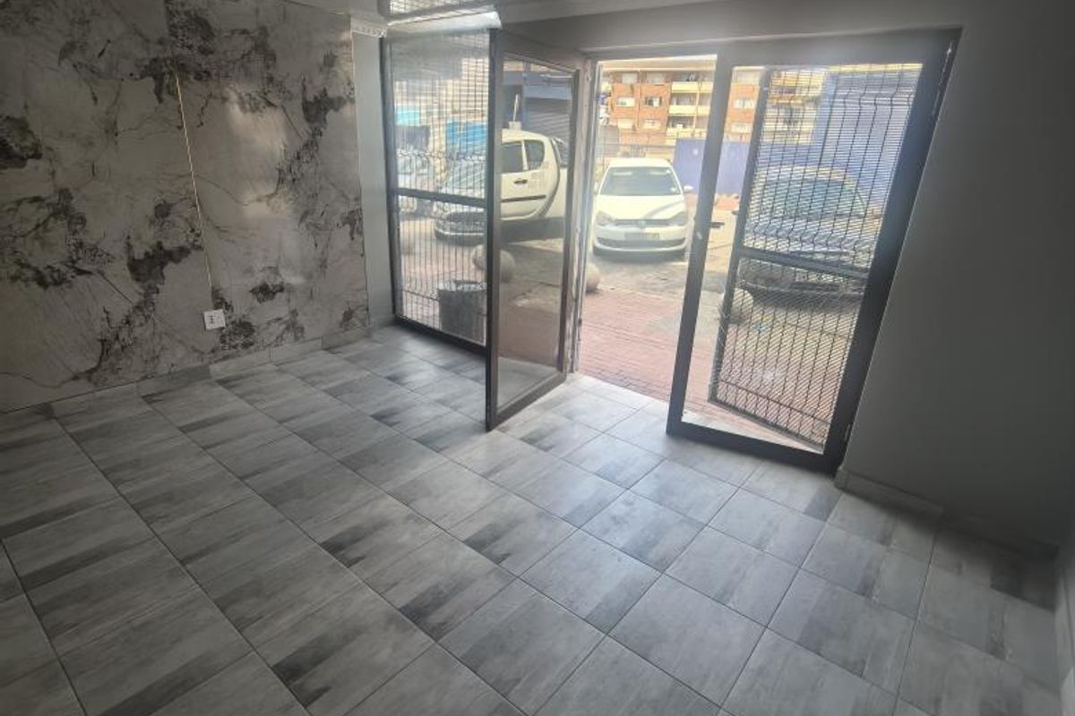 A bright entrance area featuring modern grey tiled flooring, a decorative marble-effect feature wall, and a contemporary flush-mount ceiling light fixture.