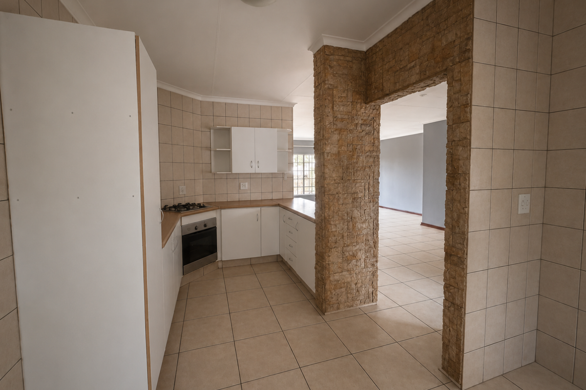 A functional kitchen featuring built-in cabinetry, a gas hob, and an oven, accented by a unique stone-clad pillar leading into the adjacent living area.