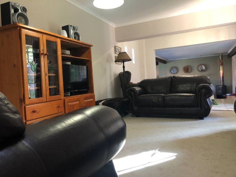 Spacious living area featuring neutral walls, coving, and a wood-burning stove in the adjacent space, offering a comfortable and functional layout.
