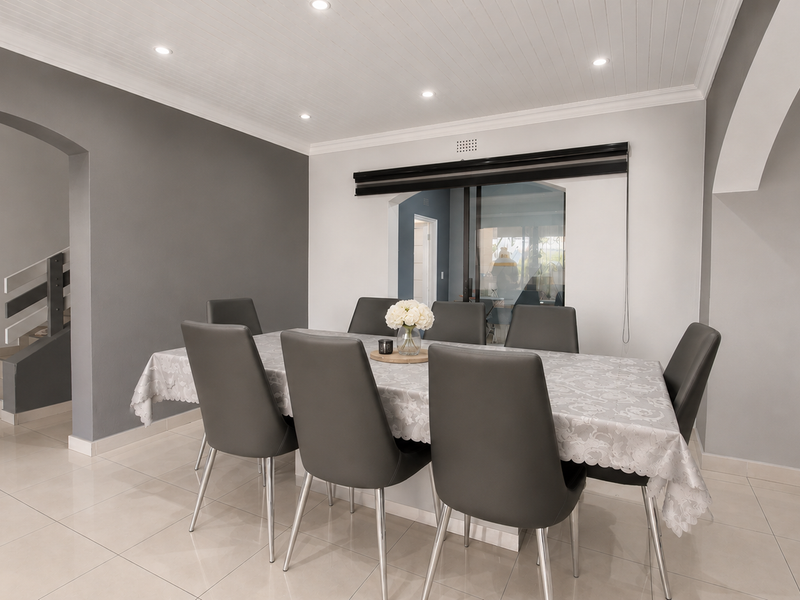 A bright dining room featuring tiled flooring, a tongue and groove ceiling with recessed lighting, and an open-plan layout with elegant archways.