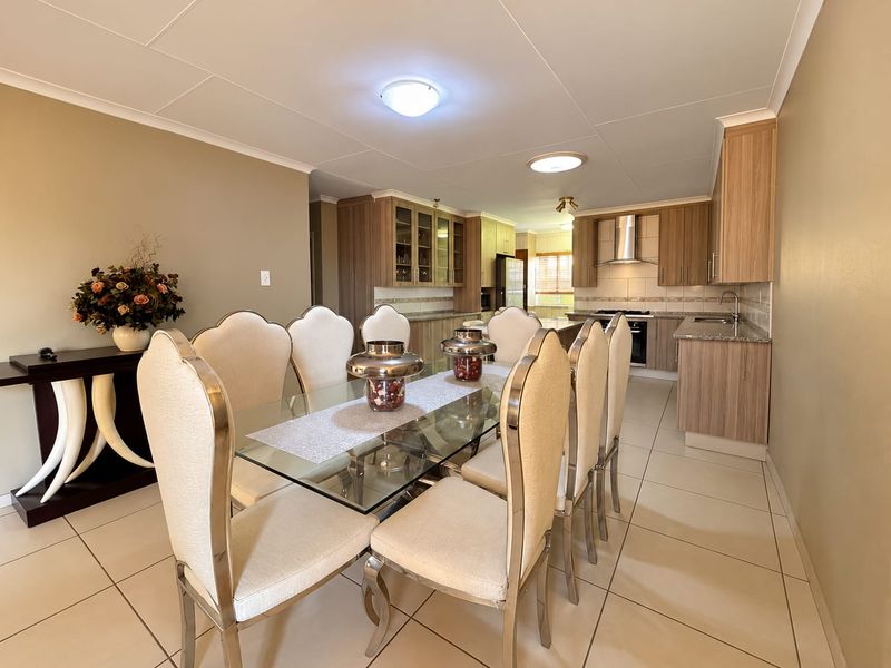 Spacious open-plan dining and kitchen area featuring modern wood-finish cabinetry, granite countertops, and tiled flooring throughout.