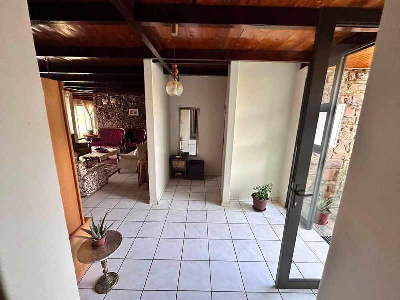 Entrance foyer featuring tiled flooring, exposed timber ceiling beams, and a stone feature wall, leading into the main living area.