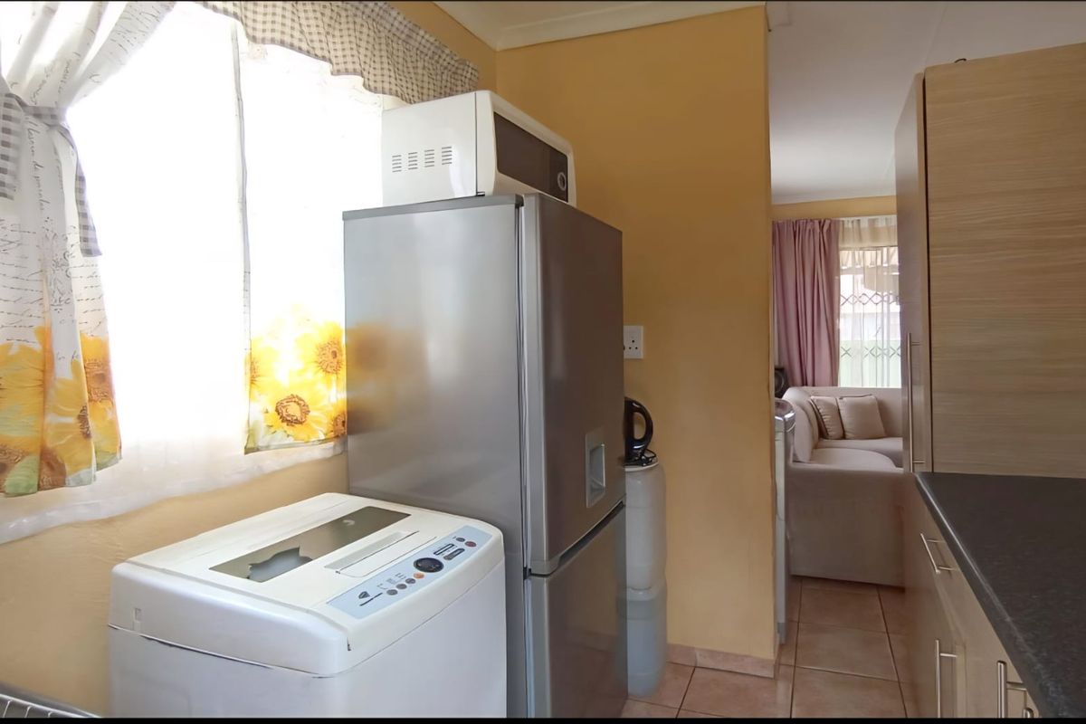 A functional kitchen area featuring tiled flooring, built-in cabinetry, and a view through to the adjacent living space.