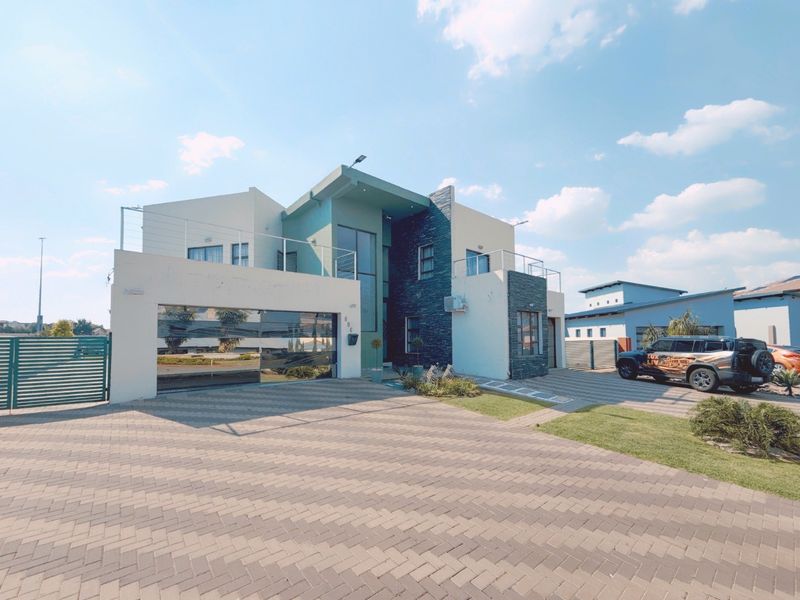 Modern double-storey residential property featuring a paved driveway, double garage, and upper-level balcony with contemporary stone and render facade finishes.