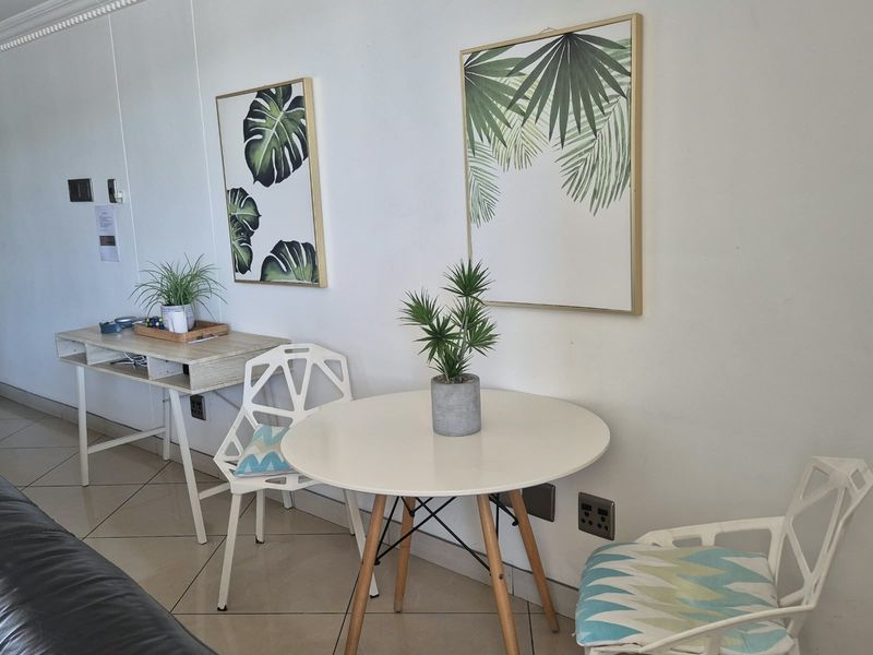 A bright living area featuring neutral tiled flooring and clean white walls, providing a versatile space for dining or relaxation.
