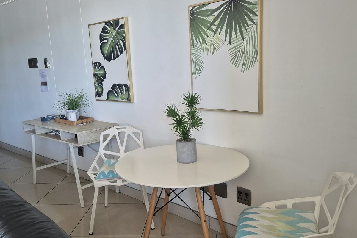 A bright living area featuring neutral tiled flooring and clean white walls, providing a versatile space for dining or relaxation.