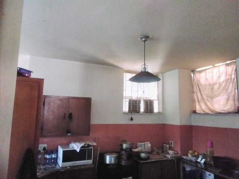 A functional kitchen space featuring built-in cabinetry, tiled splashbacks, and security bars on the windows, offering potential for modernization and aesthetic improvement.