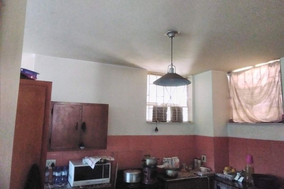 A functional kitchen space featuring built-in cabinetry, tiled splashbacks, and security bars on the windows, offering potential for modernization and aesthetic improvement.