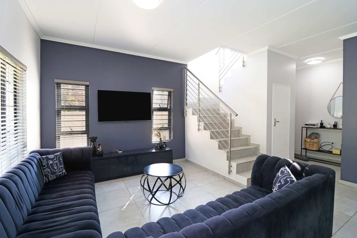 Modern living room featuring tiled flooring, a feature wall, and a staircase with stainless steel balustrades.