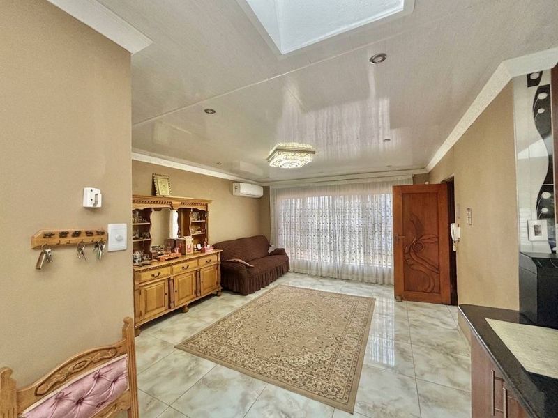 A living room featuring tiled flooring, a skylight, recessed lighting, and a wall-mounted air conditioning unit.