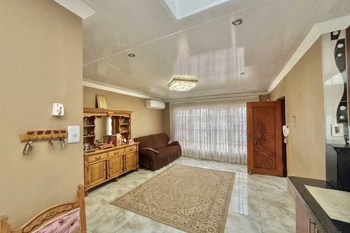 A living room featuring tiled flooring, a skylight, recessed lighting, and a wall-mounted air conditioning unit.